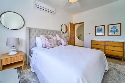 a bedroom with a large white bed and a mirror at Cana Brava Residences Rental Apartment Punta Cana in Punta Cana