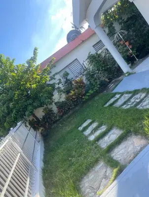 a house with a grassy yard next to a building at Your best escape in Dominican Republic!! in Santiago de los Caballeros