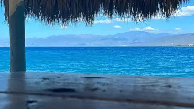a view of the ocean from a straw umbrella at Villa Rosa Bella Perfect for families or groups in Palmar de Ocoa