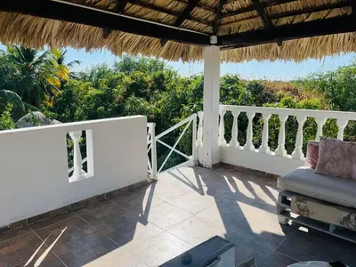 a porch with a chair and a straw roof at Villa Rosa Bella Perfect for families or groups in Palmar de Ocoa