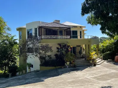 a yellow house with a porch and a balcony at La Cigua in Pedro Brand