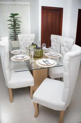 a dining room table with white chairs and a table with a bowl of fruit at Beautiful condo in La Vega in Concepción de La Vega
