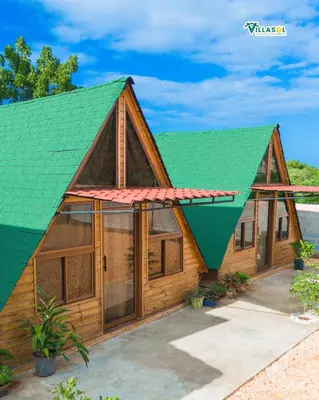 a wooden house with a green roof at Villasol Pedernales in Pedernales