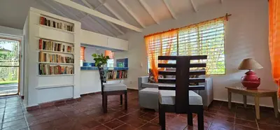 a living room with a chair and book shelves at Villa Jardín Tropical in Las Galeras