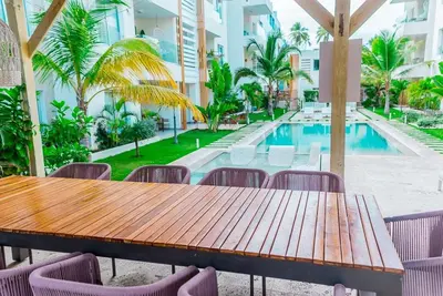 a wooden table and chairs next to a swimming pool at Punta cana apparment close to the beach in Punta Cana