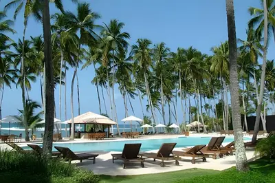 a swimming pool with lounge chairs and palm trees at Club Hemingway Amplio Apartamento en la Playa de Juan Dolio in Los Corrales