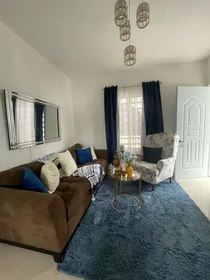 a living room with a brown couch and a blue rug at Apartamento acogedor a 5 minutos de la playa in San Felipe de Puerto Plata