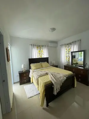a bedroom with a bed and two dressers and a mirror at Apartamento acogedor a 5 minutos de la playa in San Felipe de Puerto Plata