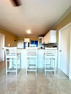 a kitchen with white bar stools and white cabinets at Itzayana 1 in Las Terrenas