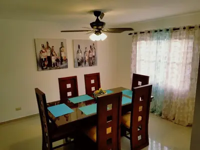 a dining room table with chairs and a ceiling fan at Cozy, comfortable three-bedroom condo in Santiago,DR in Santiago de los Caballeros