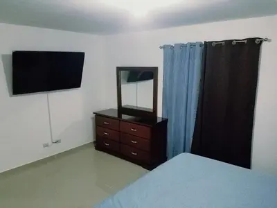 a bedroom with a dresser with a mirror and a dresser with a television at Cozy, comfortable three-bedroom condo in Santiago,DR in Santiago de los Caballeros
