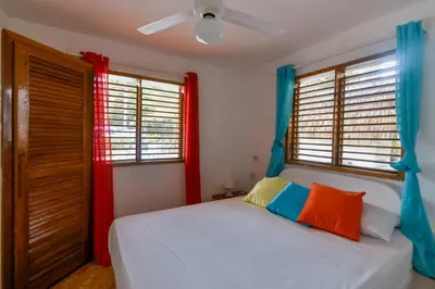 a bedroom with a bed with red and blue curtains at Paradiso del Caribe Apartments A1 and A2, Your Perfect Stay in Las Galeras in Las Galeras