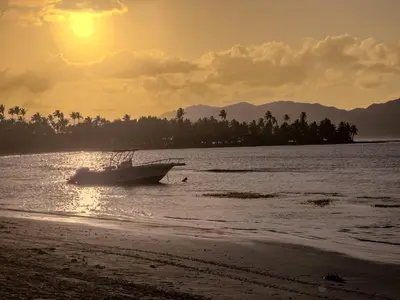 a boat in the water on a beach at sunset at Paradiso del Caribe Apartments A1 and A2, Your Perfect Stay in Las Galeras in Las Galeras
