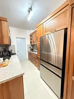 a kitchen with wooden cabinets and a stainless steel refrigerator at GH Condos by Sunrise1 in San Felipe de Puerto Plata