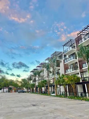 a row of apartment buildings with palm trees in a parking lot at GH Condos by Sunrise1 in San Felipe de Puerto Plata