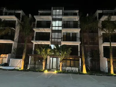 a building with palm trees in front of a parking lot at GH Condos by Sunrise2 in San Felipe de Puerto Plata