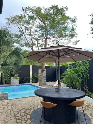 a table with an umbrella next to a pool at Santa's Villa Punta Rucia in Punta Rucia