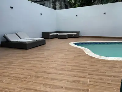 a patio with a pool and couches next to a white wall at Solano Apartamentos in Boca Chica