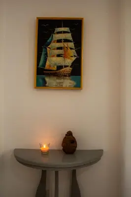 a table with a candle and a painting of a ship at Apartamento tranquilo y cómodo in La Javilla