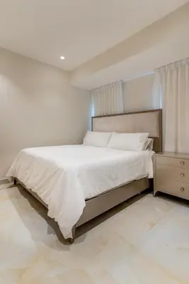 a white bedroom with a bed and a night stand at Luxury apt city views in the center of the city in Santo Domingo