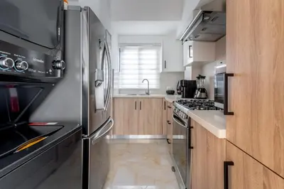 a kitchen with a stainless steel refrigerator and wooden cabinets at Luxury apt city views in the center of the city in Santo Domingo