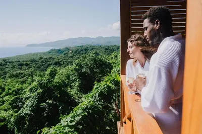 a man and a woman standing on a balcony looking out at the ocean at Araya Resort in Las Galeras