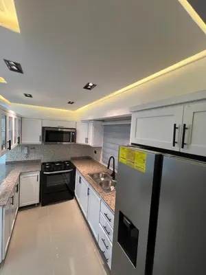 a kitchen with white cabinets and a black refrigerator at Apartamento de Lujo in La Estrella