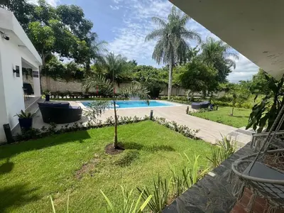 a backyard with a swimming pool and a palm tree at Villa Guavaberry in Juan Dolio