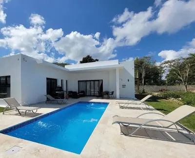 a white house with a swimming pool and chairs at Villa Tranquila - Sosua Ocean Village in Sosúa