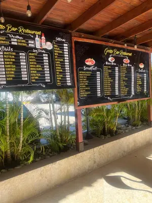 a sign for a fast food restaurant with plants at Laguna beach in Sosúa