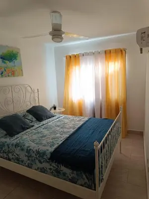 a bedroom with a bed with a blue blanket and a window at Apartment in Riviera Colonial in Calero