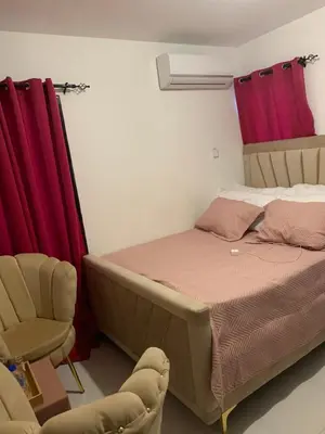 a bed and a chair in a room with red curtains at Cómodo y acogedor in Los Paredones