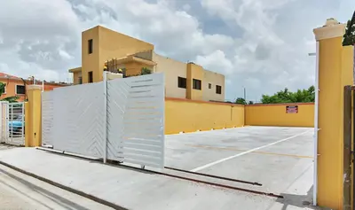 a gate in a parking lot in front of a building at Apartahotel Santo Domingo EsteRD - Aeropuerto Las Americas in La Viva