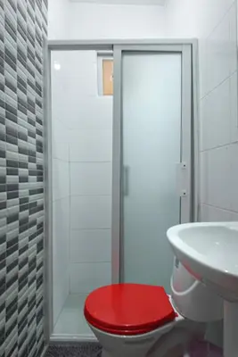 a bathroom with a toilet with a red seat at Apartahotel Santo Domingo EsteRD - Aeropuerto Las Americas in La Viva