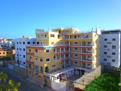 a tall yellow building on the side of a street at Apartahotel Santo Domingo EsteRD - Aeropuerto Las Americas in La Viva