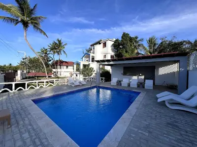 a swimming pool with white chairs and a house at Front Beach Punta Rucia Villa in Punta Rucia