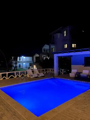 a swimming pool at night with chairs and a building at Front Beach Punta Rucia Villa in Punta Rucia