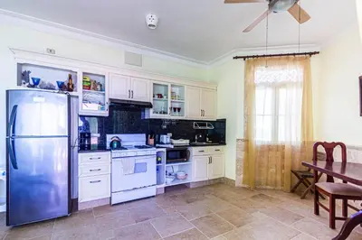 a kitchen with white cabinets and a table and a refrigerator at Oceanfront Apartment in Cabarete with Pool and Beach Access in Cabarete
