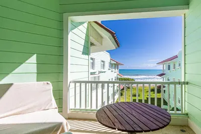 a balcony with a bed and a view of the ocean at Oceanfront Apartment in Cabarete with Pool and Beach Access in Cabarete