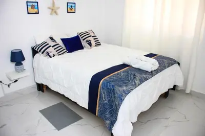 a bedroom with a bed with white sheets and pillows at Residencia Bambou HAVRE DE PAIX in Juan Dolio