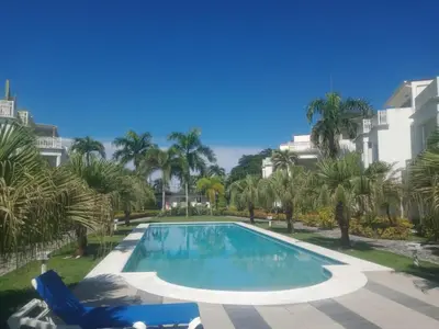 a swimming pool with palm trees and a building at Apartment mit Meerblick direkt an der Playa Popy in Las Terrenas