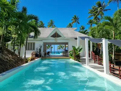 a villa with a swimming pool in front of a house at Beachfront Villa Tabiki at Playa Coson, Las Terrenas, Dominicana in Las Terrenas