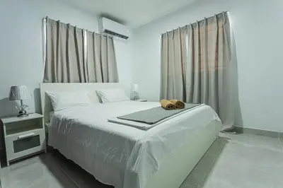 a white bedroom with a bed with a hat on it at America Apartment in Santo Domingo