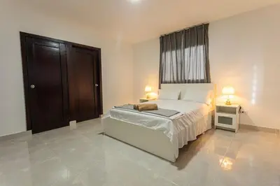 a bedroom with a bed and a window and two lamps at America Apartment in Santo Domingo