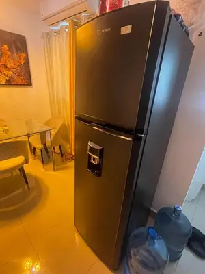 a black refrigerator with two plastic water bottles in front of it at Apartamento Bello y Amueblado in Jacagua