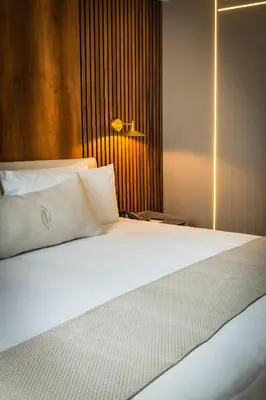 a bedroom with a large white bed and a lamp at Nohian Collection Hotels in Santiago de los Caballeros