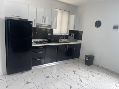 a kitchen with a black refrigerator and white cabinets at Level Suites 3 Premium Suite in Sosúa