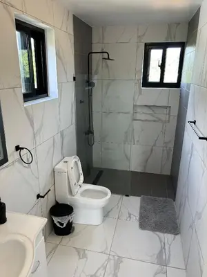 a white bathroom with a shower and a toilet at Level Suites 3 Premium Suite in Sosúa