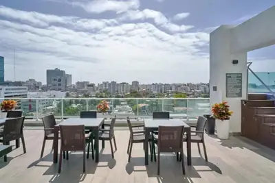 a balcony with tables and chairs and a view of the city at Luxury and Cozy Places QDA-II in Santo Domingo