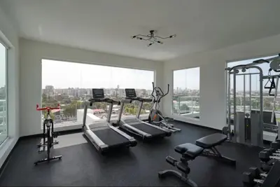 a gym with treadmills and ellipticals in a room with windows at Luxury and Cozy Places QDA-II in Santo Domingo